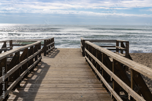 wooden boardwalk and beach access leads directly onto beach with stormy waves and skies