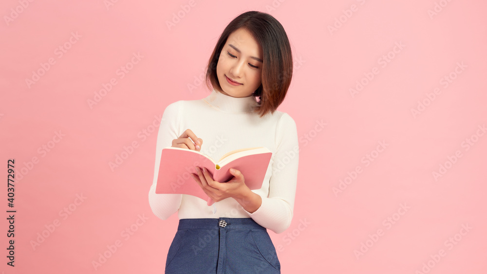 Photo of pretty lady hold book planner first writing notes isolated on pink color background Photo of pretty lady hold book planner first writing notes isolated on pink color background