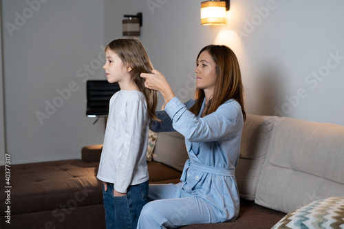 portrait of happy little adorable girl spending time with her beautiful mother at home, combing her hair