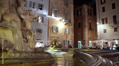 Architectural heritage of Roman city, antique marble fountains with fish sculptures decorating city street and inspirating citizens and tourists. Roman downtown at night, sightseeing concept photo