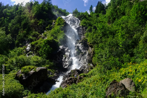 high waterfall between rocks and green shrubs in the mountains © thomaseder