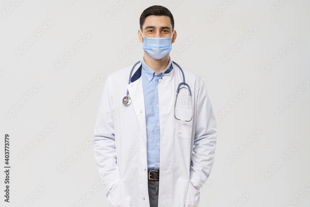 Portrait of male doctor wearing surgical mask is ready to help patients with coronavirus or covid virus, isolated on gray background