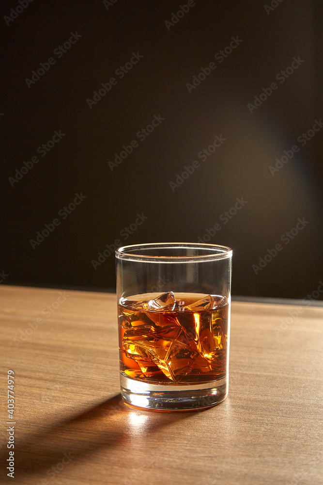 A Glass of whiskey on ice on wood table A Glass of whiskey on ice on wood table