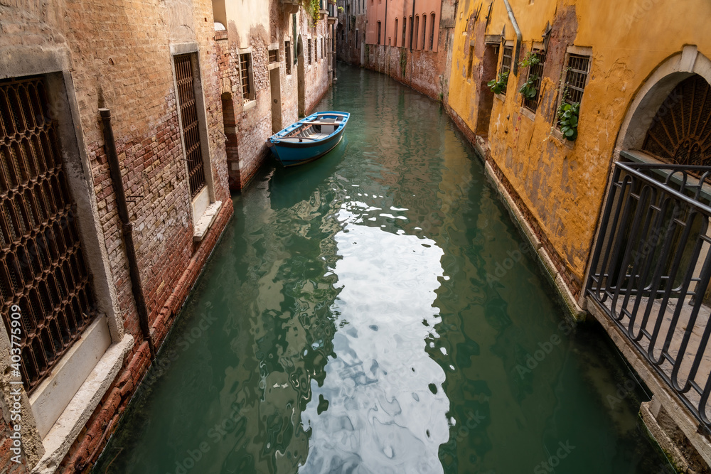 ein schmaler Kanal in San Polo, Venedig mit einem blauen Boot in grünem Wasser