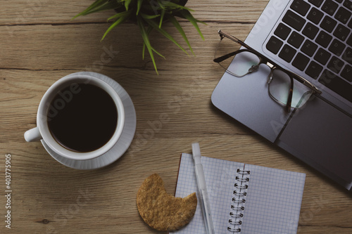 Top view modern office table desk with office supplies like laptop, eyeglass, cup of coffee and notes bloc. Desktop workspace. Wood texture background. 