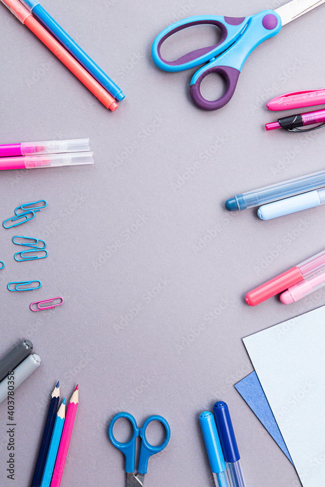 Various stationery in pink and blue colors, blank sheets of paper, on a gray background with copy space. Flat lay with pencils, scissors, pens, paper clips, felt-tip pens and sheets of paper. Various stationery in pink and blue colors, blank sheets of paper, on a gray background with copy space. Flat lay with pencils, scissors, pens, paper clips, felt-tip pens and sheets of paper.