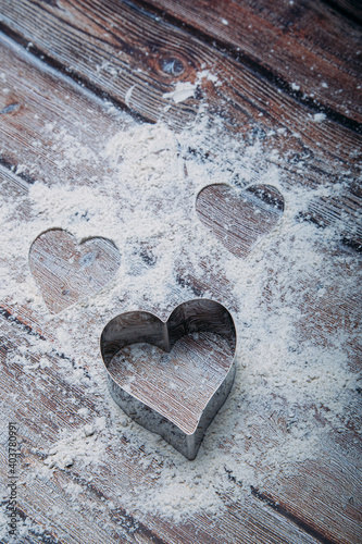 Heart shaped cookie cutter on the kitchen table and flour. Valentine's Day concept. Vertical Image