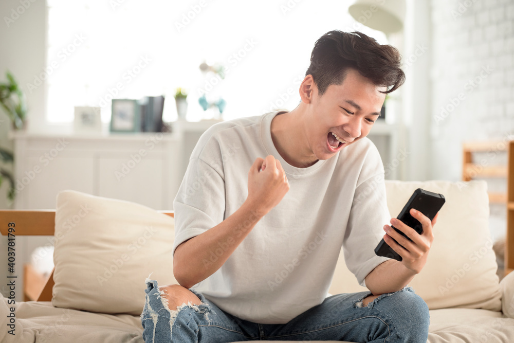 happy young man  looking at cell phone celebrate receiving  good news