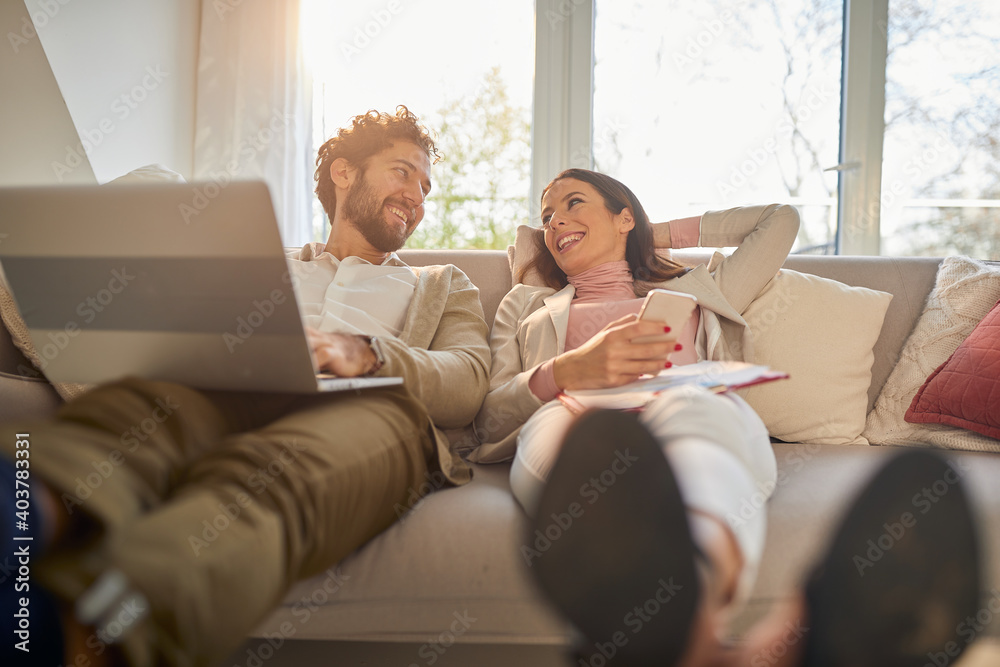 A young business couple enjoying on a couch in an apartment after a working day. Business, couple, leisure, together A young business couple enjoying on a couch in an apartment after a working day. Business, couple, leisure, together