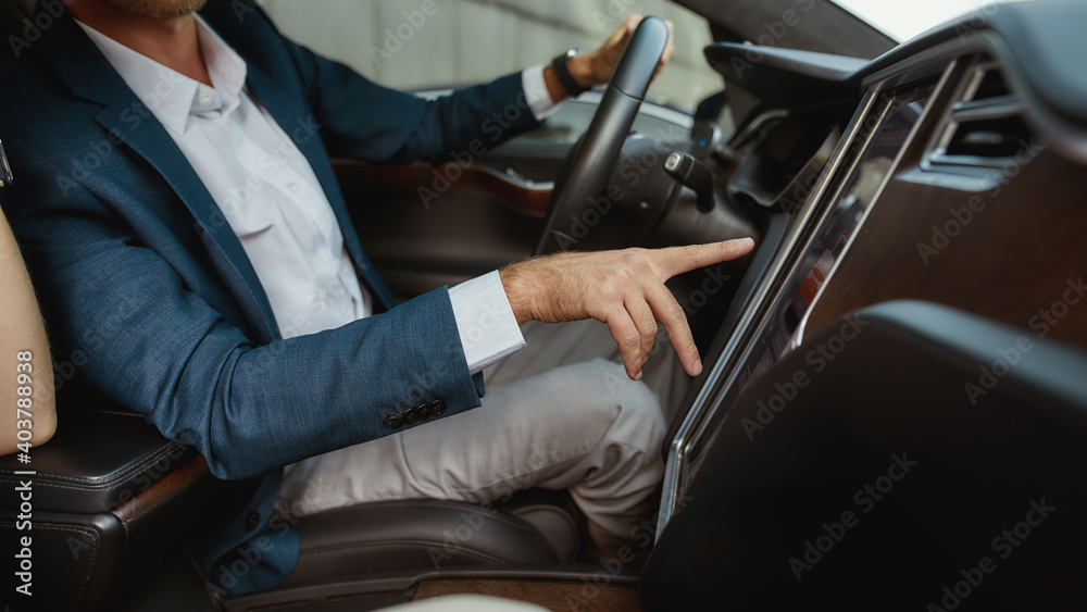 Young businessman using car computer inside luxury car