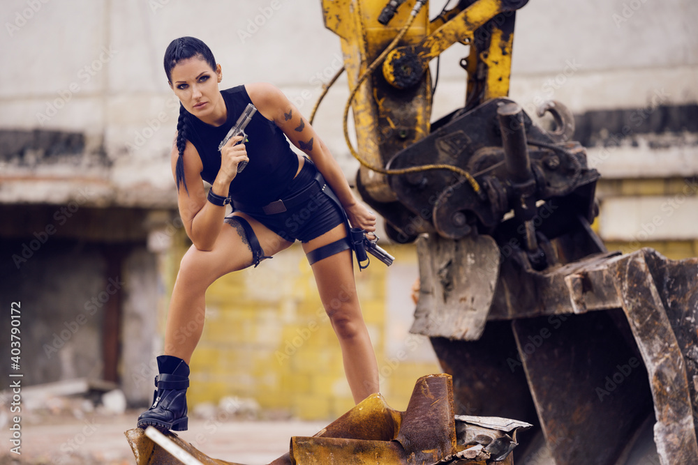 Lara Croft Tomb Raider action movie cosplay costume photoshoot with guns  and weapons brunette female model Stock Photo