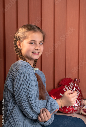 Beautiful girl with pigtails holding a heart shaped lollipop