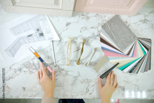 Home improvement concept. Girl the designer chooses the facades and handles for cabinet furniture in a store showroom. decors boards on the furniture industry. Choosing samples of materials