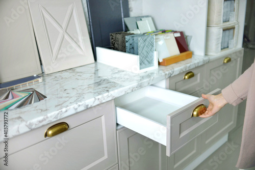 Home improvement concept. young girl designer opens a drawer of a kitchen cabinet in a shop salon.