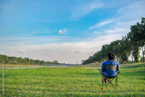 Young man in medical mask sitting on a chair  in the park . Covid-19 coronavirus pandemic. Active quarantine life in the Corona outbreak. © chartphoto