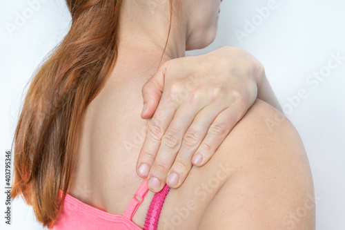 Woman with shoulder pain is holding her aching shoulder