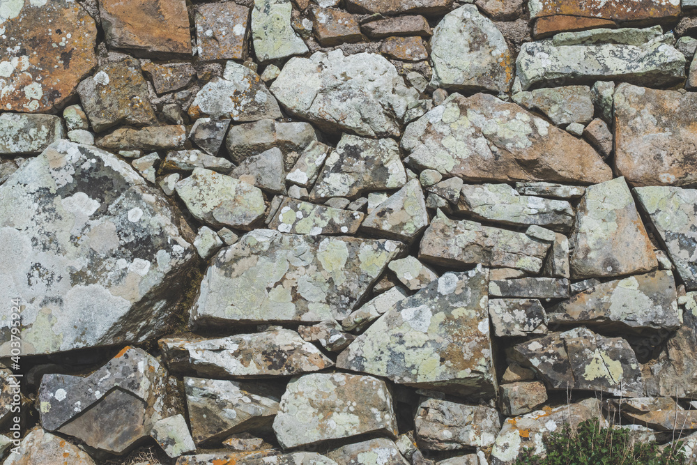 Old stone rock wall surface texture with grass. Close up detail. Pattern abstract background. Old stone rock wall surface texture with grass. Close up detail. Pattern abstract background.