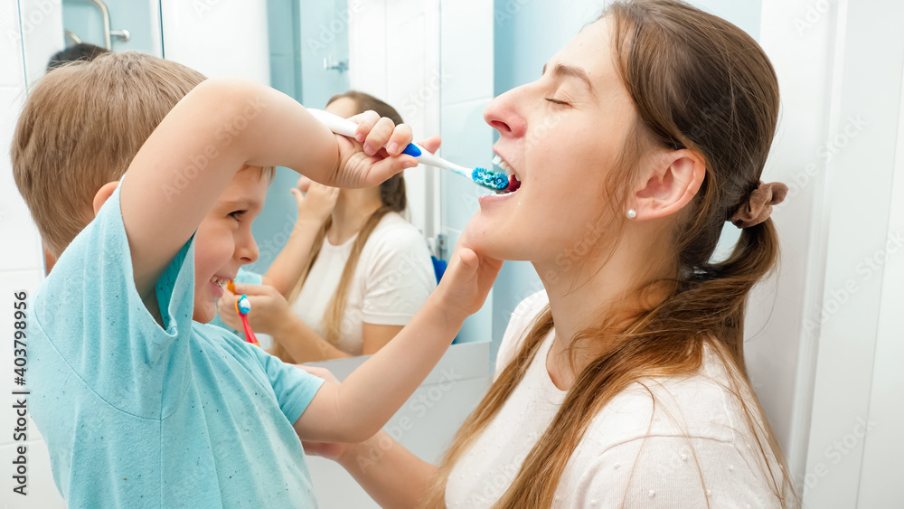 Little toddler boy brushing and cleaning teeth to his mother in bathroom Little toddler boy brushing and cleaning teeth to his mother in bathroom