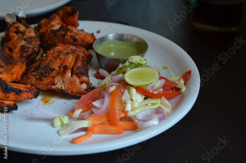 Indian food. Red chicken in tandoor with fresh vegetables vegetables and delicious naan with cheese