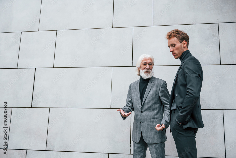 Young guy with senior man in elegant clothes is outdoors together. Conception of business Young guy with senior man in elegant clothes is outdoors together. Conception of business