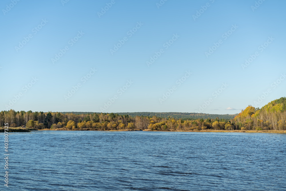 Natural landscape with a lake and autumn trees on the shore.