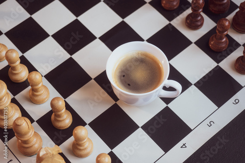 Chessboard and chess pieces on the table with coffee cups