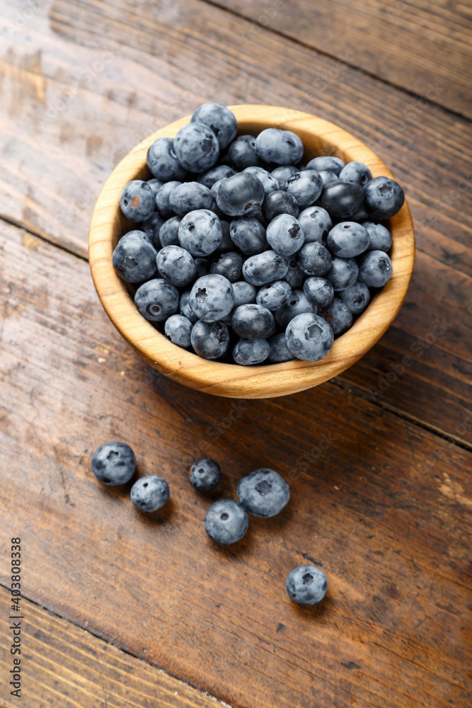 Freshly picked blueberries in wooden bowl on wooden background. Concept of healthy and dieting eating. Freshly picked blueberries in wooden bowl on wooden background. Concept of healthy and dieting eating.