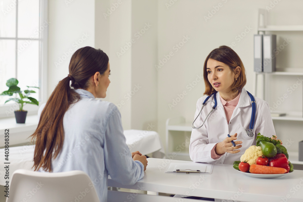 Fototapeta premium Female nutritionist makes a healthy diet plan for a patient who has come for nutrition advice. Woman consults about her health. Concept of healthy lifestyle and food, medicine and treatment.