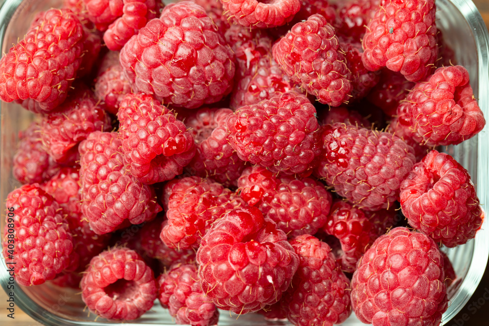 Ripe raspberry in a glass plate, place for text, summer harvest of berries Ripe raspberry in a glass plate, place for text, summer harvest of berries