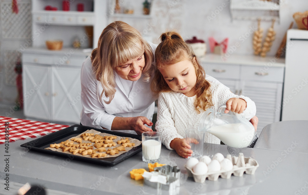 Finished product. Senior grandmother with her little granddaughter cooks sweets for Christmas on the kitchen Finished product. Senior grandmother with her little granddaughter cooks sweets for Christmas on the kitchen