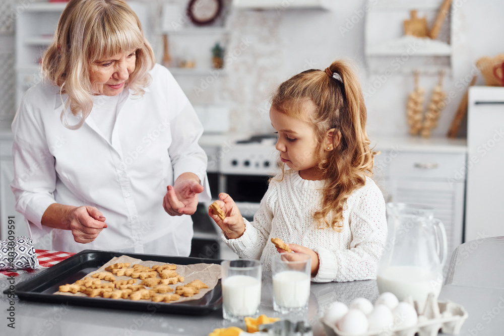 Finished product. Senior grandmother with her little granddaughter cooks sweets for Christmas on the kitchen Finished product. Senior grandmother with her little granddaughter cooks sweets for Christmas on the kitchen