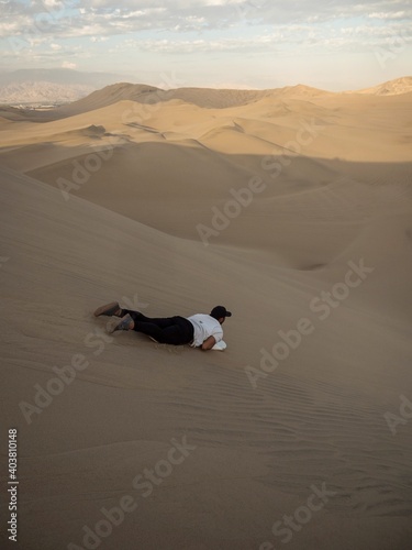 Tourist sliding down slopes of Huacahina sand dunes sandboarding adventure adrenaline fun extreme sports Ica Peru photo