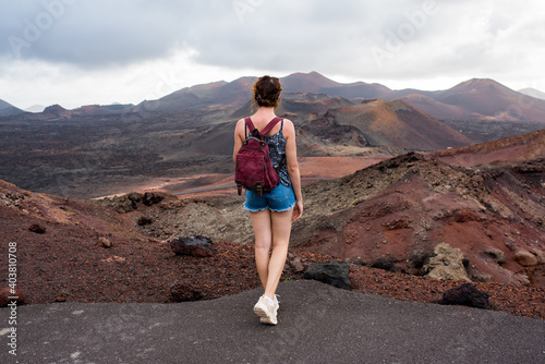Young woman with a backpack contemplating the volcanic area Timanfaya Natural Park, in Lanzarote, travel photography photo