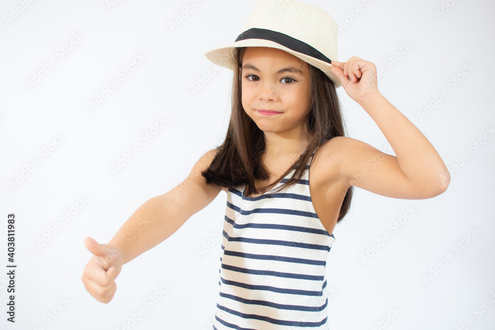 Beautiful smiling little girl in striped t-shirt and straw hat showing thumb up over white background. Beautiful smiling little girl in striped t-shirt and straw hat showing thumb up over white background.