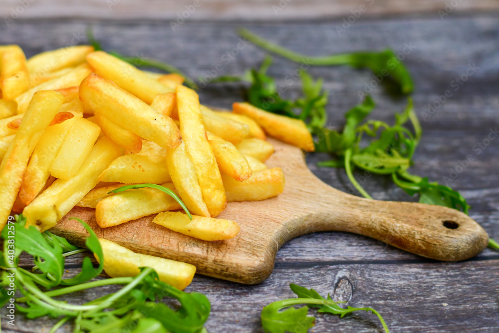 Home made organic french fries and fresh aragula on wooden background Home made organic french fries and fresh aragula on wooden background