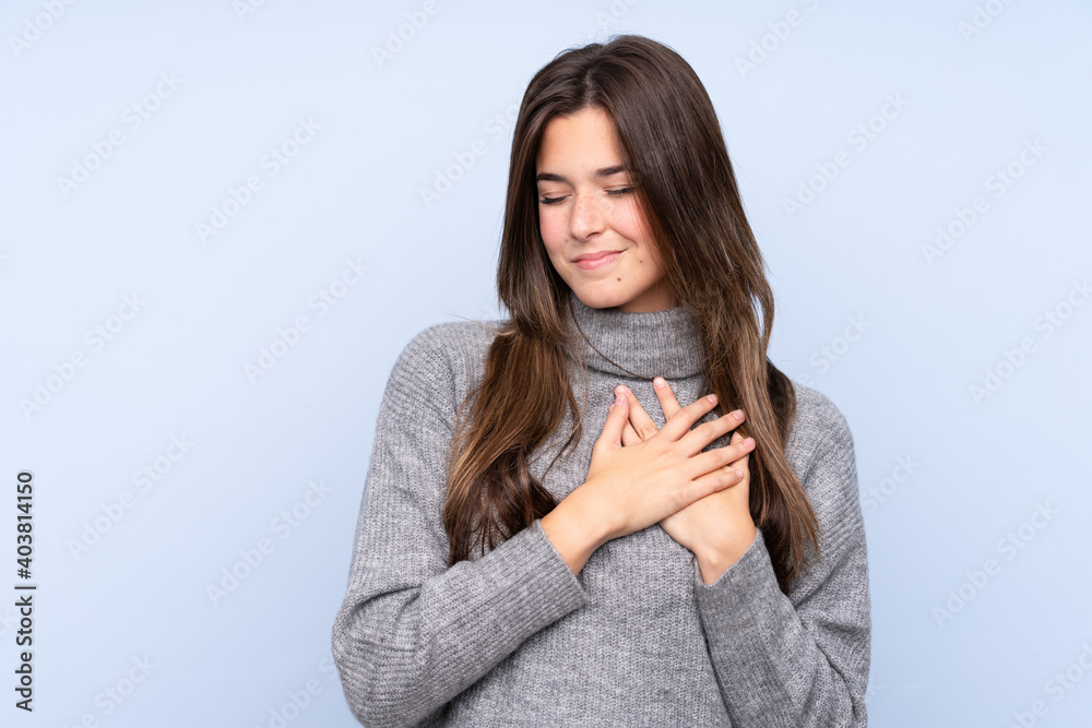 Teenager Brazilian girl over isolated blue background having a pain in the heart Teenager Brazilian girl over isolated blue background having a pain in the heart