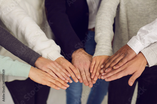 Group of mixed race people joining hands as symbol of team spirit. Concept of power, unity, corporate social responsibility, mutual support and reaching goals together. Human hands in close-up