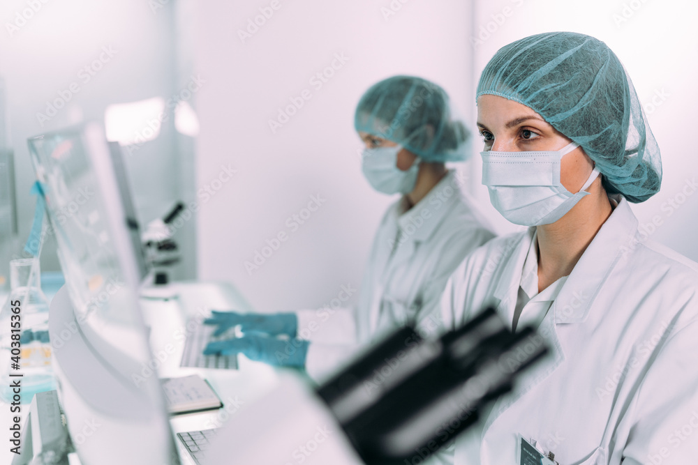 Young, female doctors working in futuristic laboratory. Using computers and microscopes Young, female doctors working in futuristic laboratory. Using computers and microscopes