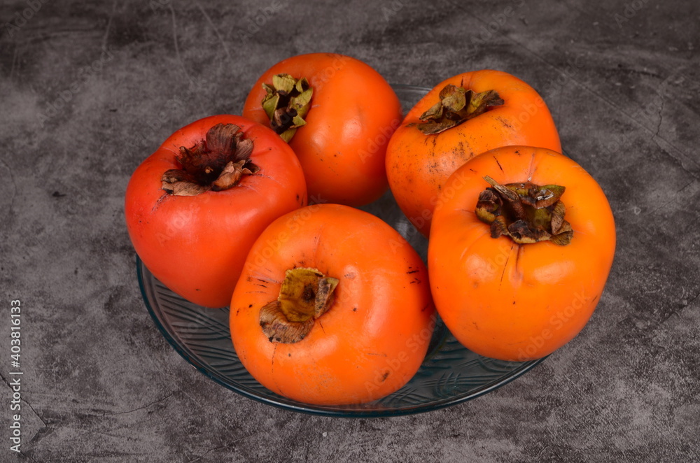 Group of Ripe orange persimmon fruit.Persimmon fruits in plate, rustic background, Hurma fruit Group of Ripe orange persimmon fruit.Persimmon fruits in plate, rustic background, Hurma fruit