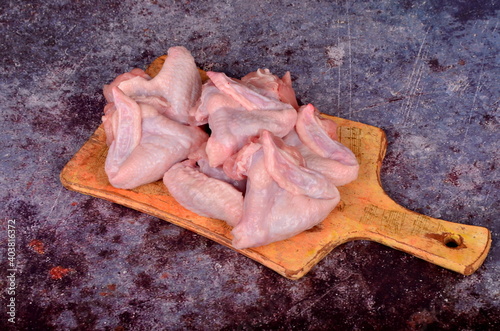 Fresh raw chicken wings on kitchen wooden board with ingredients and spices