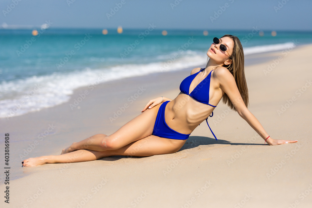 Summer lifestyle. Portrait of pretty girl with slim tanned sexy body in bikini enjoying life and lying on the sand on the beach of tropical island. Vacation Summer lifestyle. Portrait of pretty girl with slim tanned sexy body in bikini enjoying life and lying on the sand on the beach of tropical island. Vacation