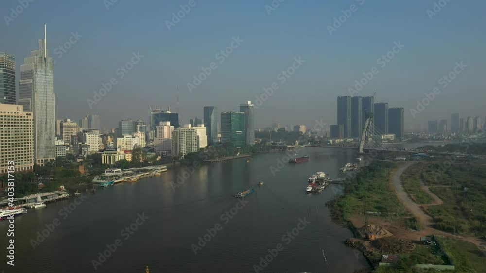 Drone view of Saigon River, Ho Chi Minh City and new Thu Thiem Bridge under construction on a sunny day. Flying across the river to bridge and buildings Drone view of Saigon River, Ho Chi Minh City and new Thu Thiem Bridge under construction on a sunny day. Flying across the river to bridge and buildings