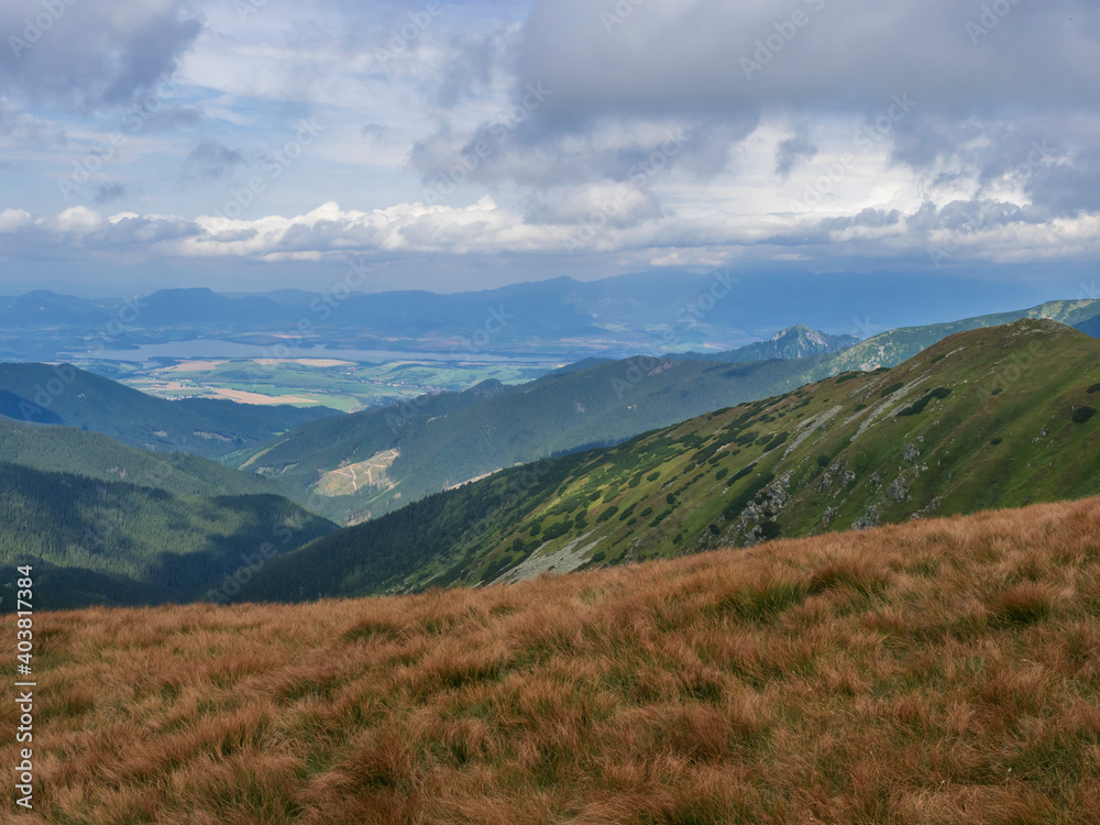 View from grassy hill slopes of hiking trail from Chopok at mountain meadow landscape of ridge Low Tatras mountains Nature park, Slovakia. cloudy late summer day