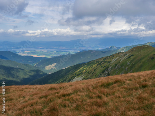 View from grassy hill slopes of hiking trail from Chopok at mountain meadow landscape of ridge Low Tatras mountains Nature park, Slovakia. cloudy late summer day