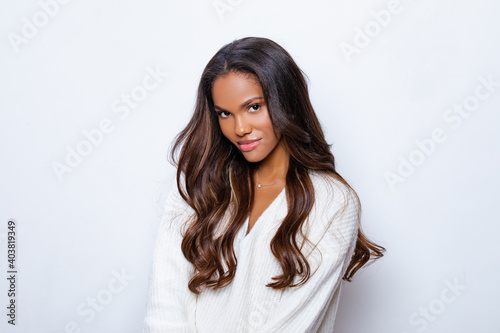 Happy Black Girl Smile in White Sweater with long curly hair. Relaxed and Carefree. Portrait of beautiful black woman in whit sweater with long curly hair. 