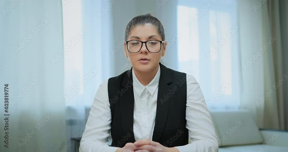 Concentrated student in glasses and classic suit looks into computer camera and nods sitting at online lecture during quarantine Concentrated student in glasses and classic suit looks into computer camera and nods sitting at online lecture during quarantine