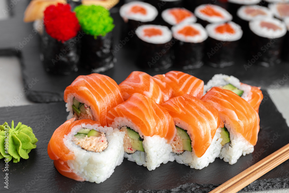 Sushi roll covered with fresh salmon served on plate Sushi roll covered with fresh salmon served on plate