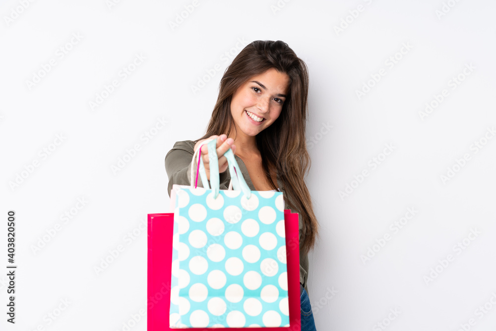 Teenager Brazilian girl with shopping bag over isolated white background with happy expression Teenager Brazilian girl with shopping bag over isolated white background with happy expression
