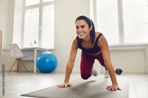 Home workout with no equipment. Beautiful active sports woman trains on a mat and does leg exercises at home during quarantine. Fitness, sport, training and lifestyle concept.