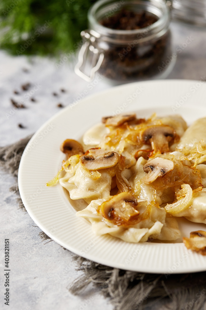 Christmas dumplings stuffed with mushrooms and cabbage on a white plate on a rustic wooden table. A traditional dish on Christmas Eve in Poland. Dumplings, dumplings, pies, pies - stuffed dumplings. Christmas dumplings stuffed with mushrooms and cabbage on a white plate on a rustic wooden table. A traditional dish on Christmas Eve in Poland. Dumplings, dumplings, pies, pies - stuffed dumplings.